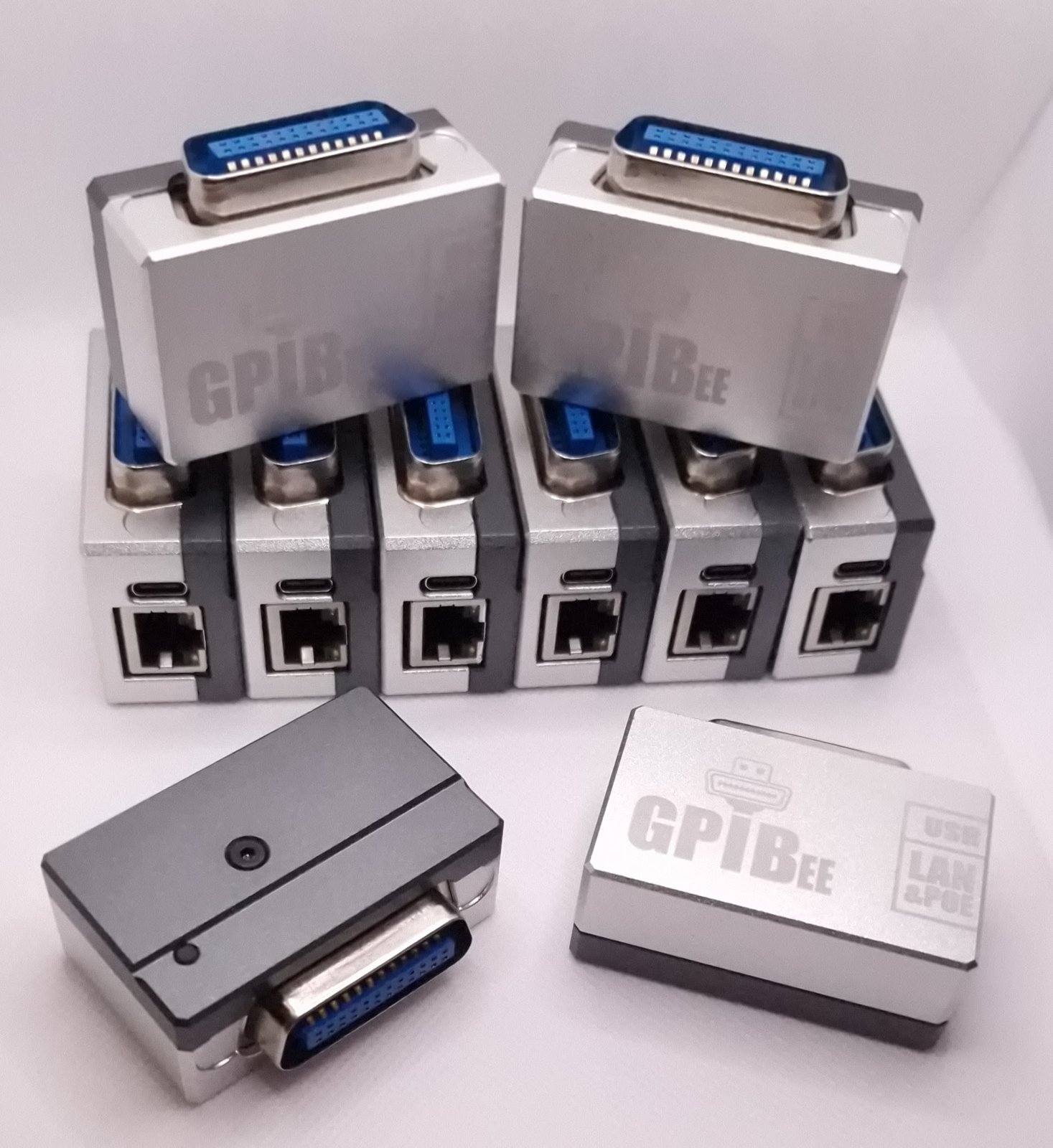 Multiple GPIBee adapters showing the IEEE-488 connector, USB-C port, and RJ45 Ethernet jack